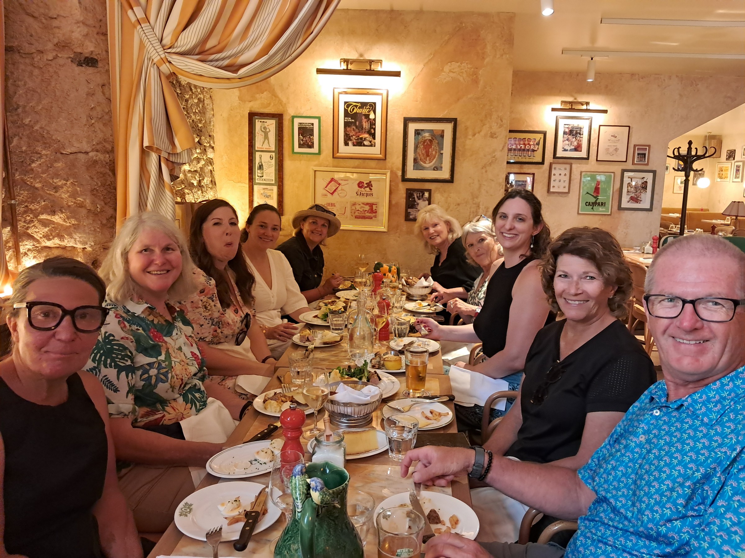 Group of people smiling at a dining table in a warmly lit restaurant.