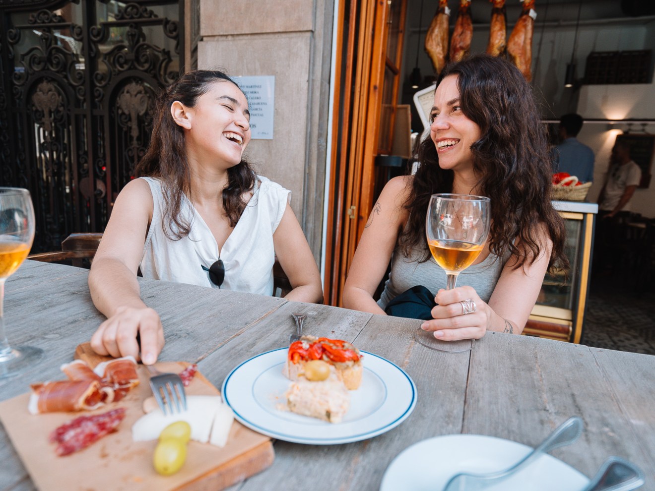 a woman sitting at a table eating and drinking wine