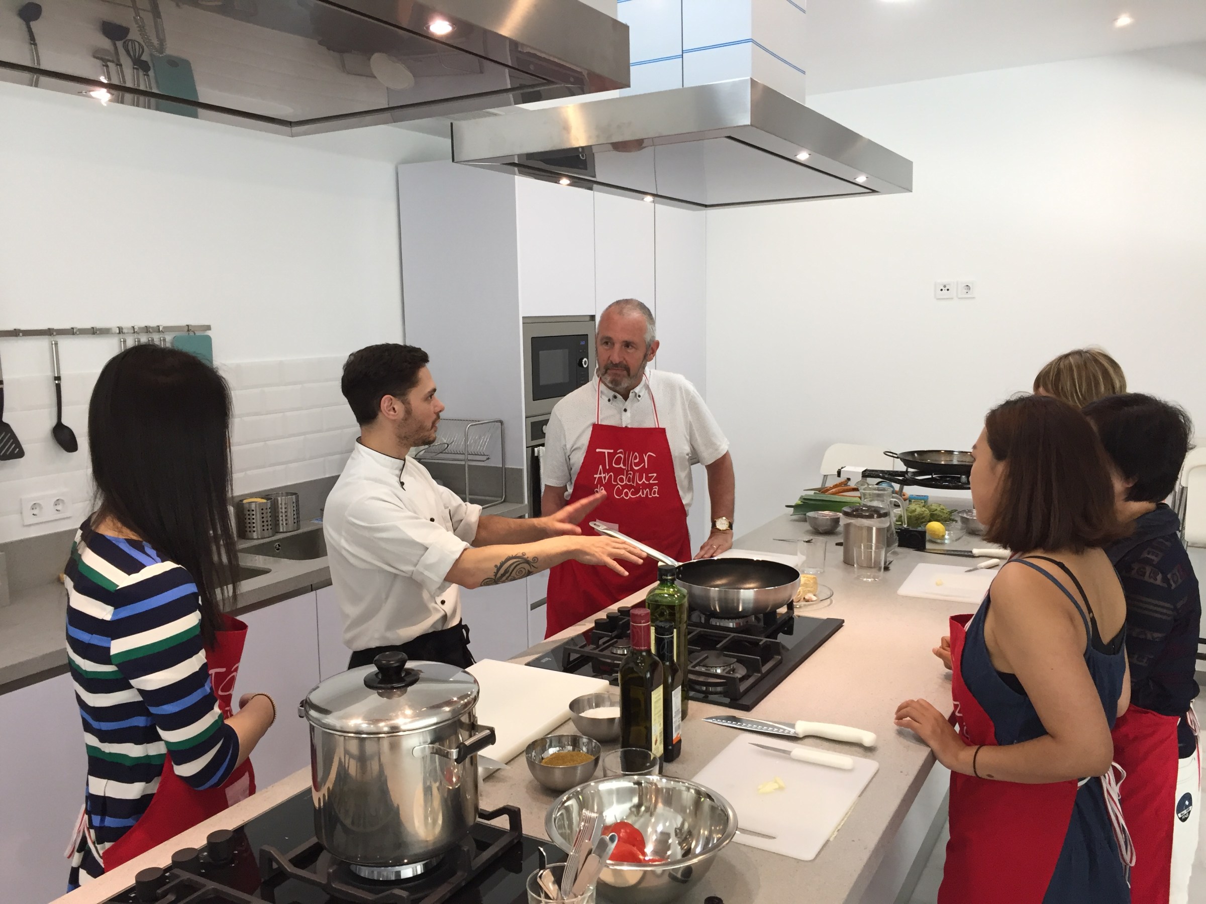 Chef instructing a cooking class with participants in a modern kitchen.