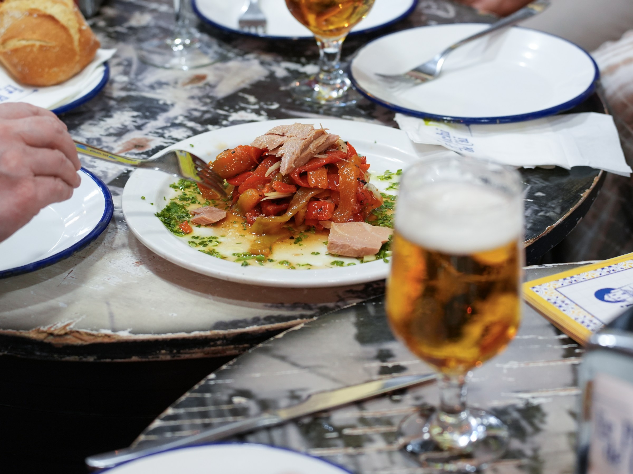 Plate of meat and vegetables on table with drinks and bread.