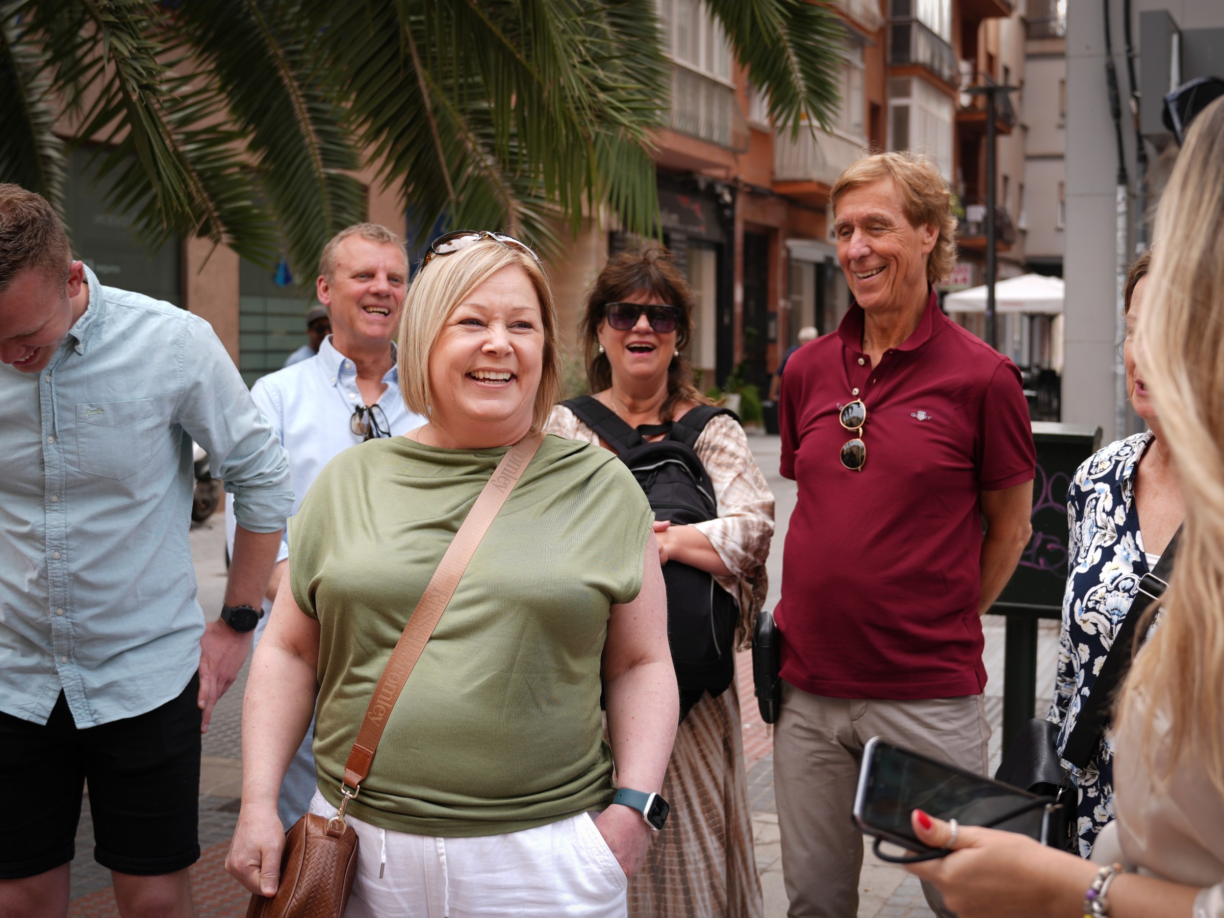 Smiling group of people standing outdoors in a city street.