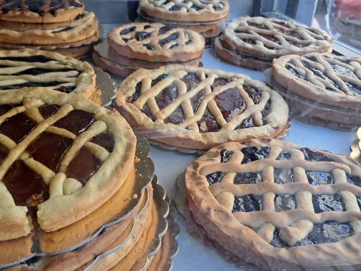 Several lattice-topped pies with assorted fillings displayed in a bakery window.