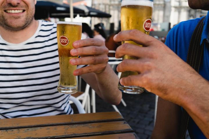 a man holding a glass of beer on a table