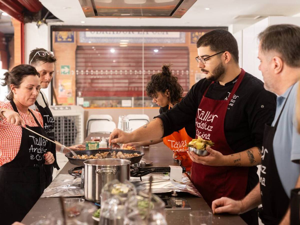 Group cooking class with participants and instructor around a kitchen counter.
