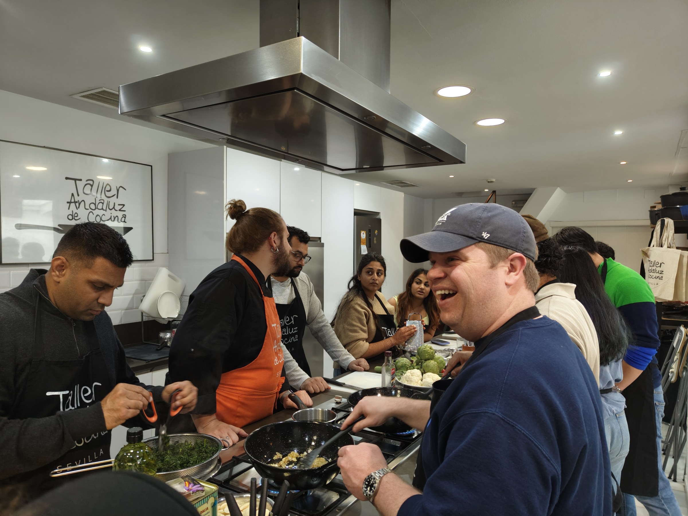 Group cooking class with people gathered around a central kitchen island.