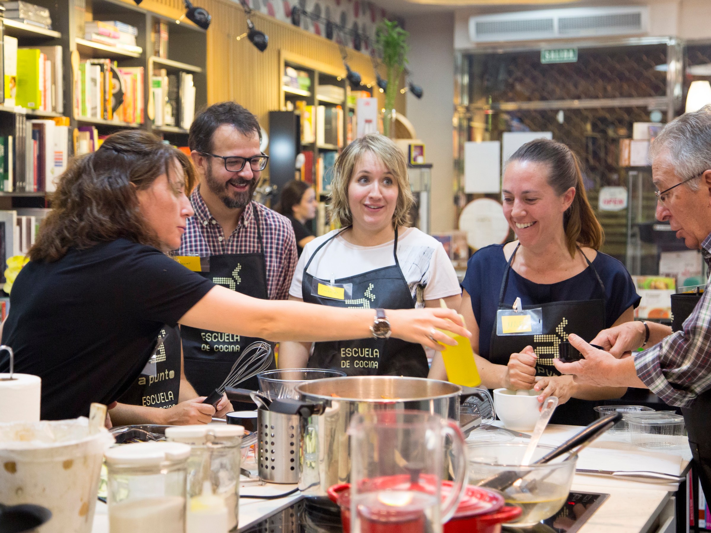 Group of people cooking together in a kitchen classroom.