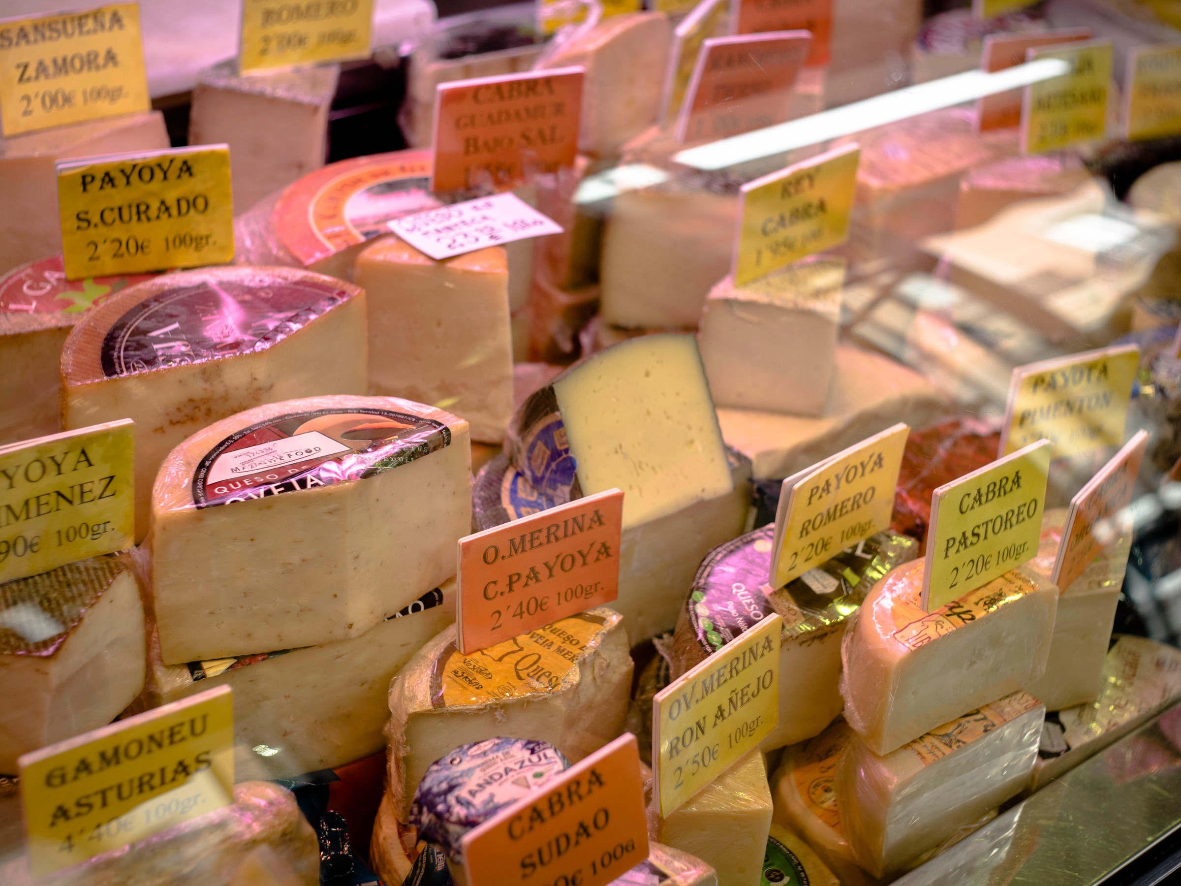 Various cheeses with labels in a display case.