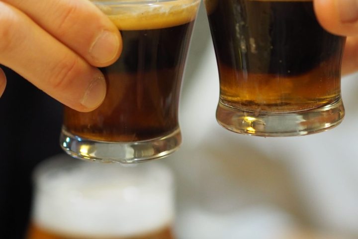 a hand holding a glass of beer on a table