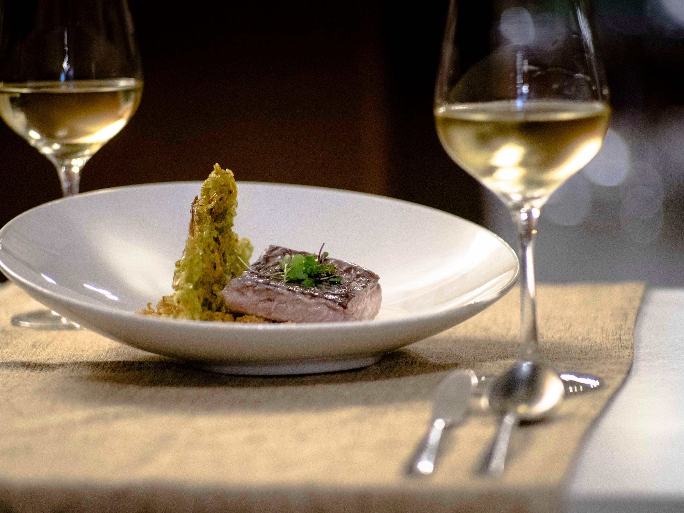 a close up of a plate of food and glasses of wine