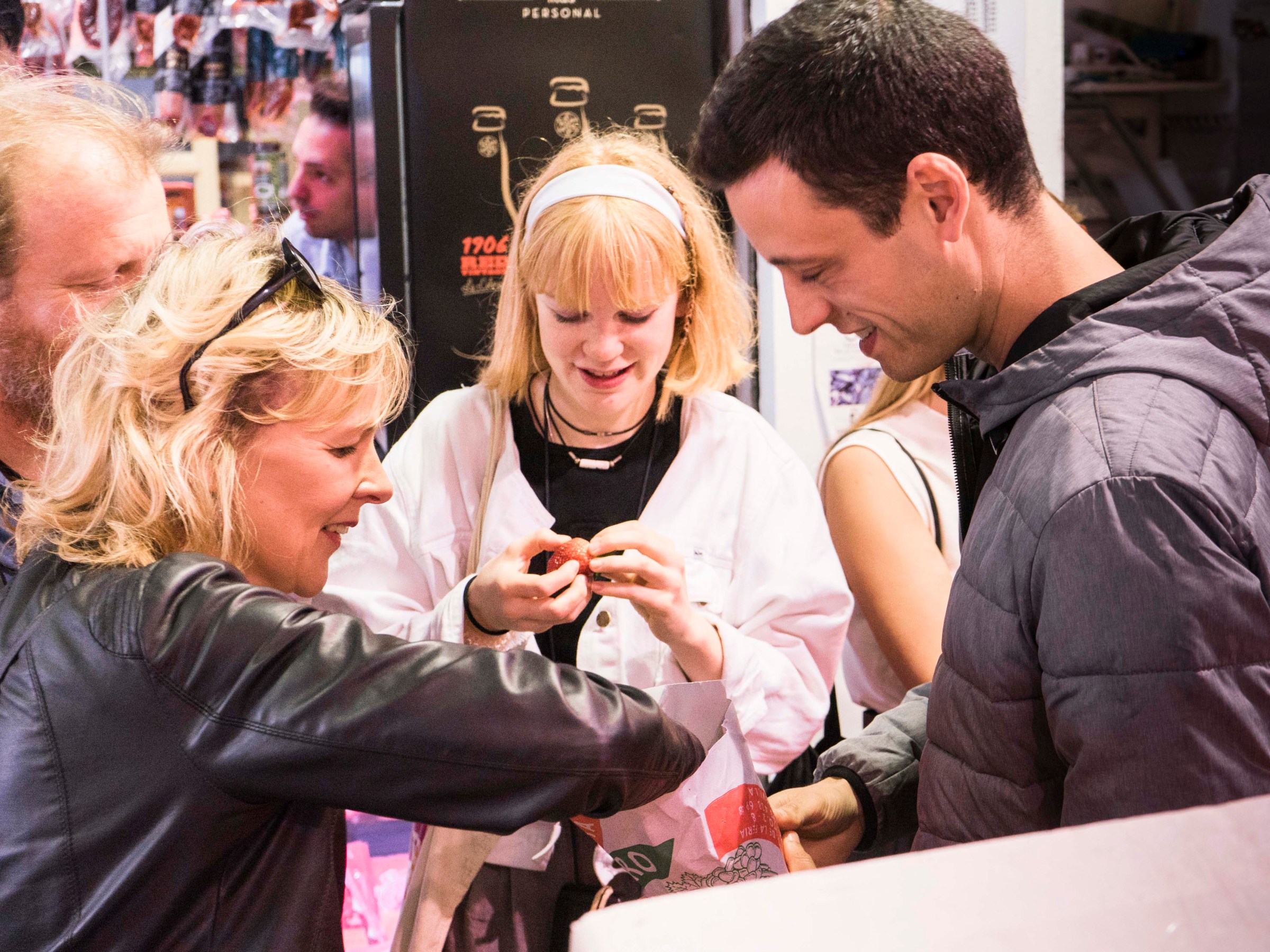 Group of people smiling and interacting in a busy indoor setting.