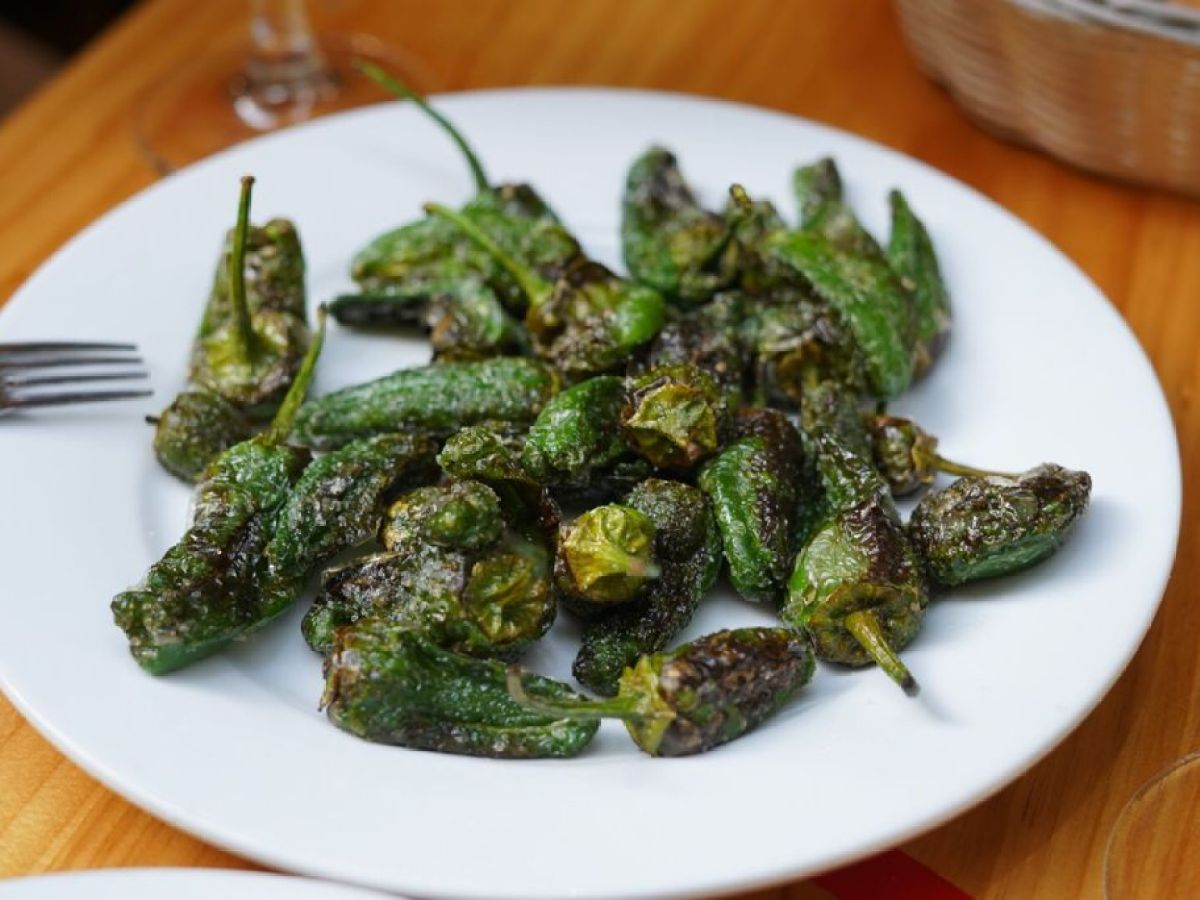 Plate of cooked green peppers on a wooden table.