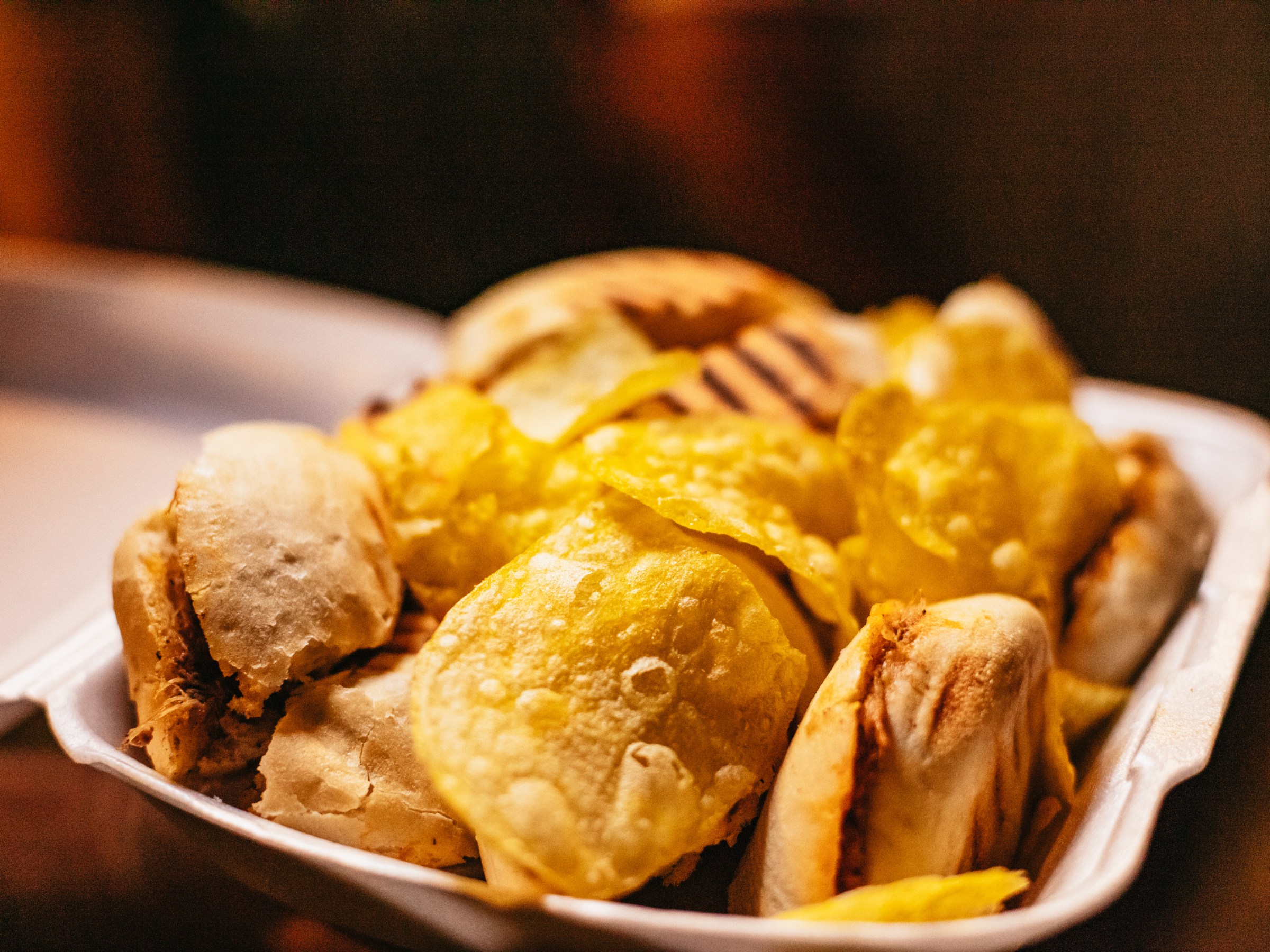 Close-up of grilled sandwiches and chips in a foam container.