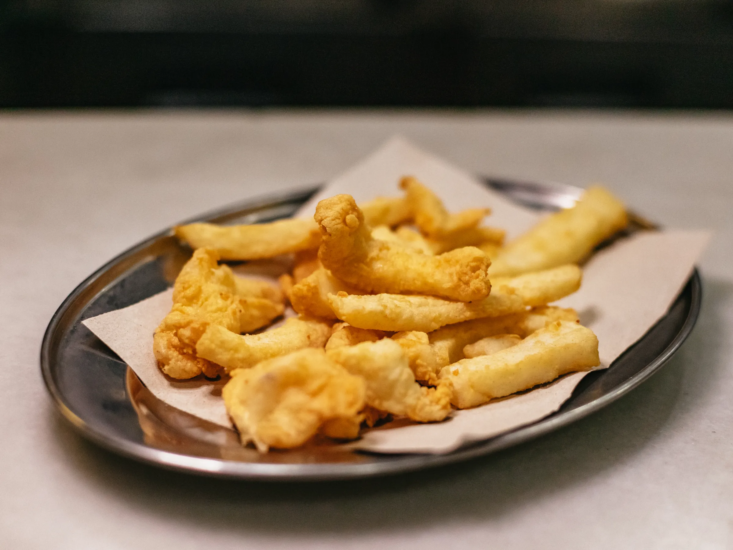 A metal plate with pieces of fried food on a napkin.