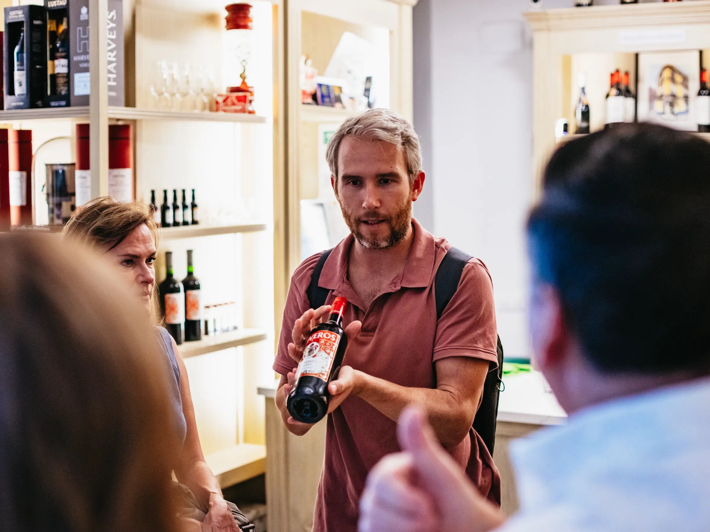 Man showing a wine bottle to a small group in a store.