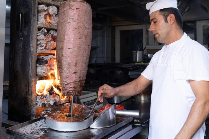 a man cooking hot dogs on a grill