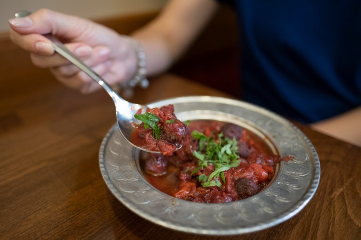 a person holding a plate of food on a table