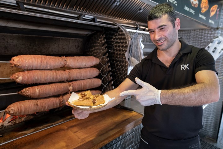 a man holding a hot dog on a grill