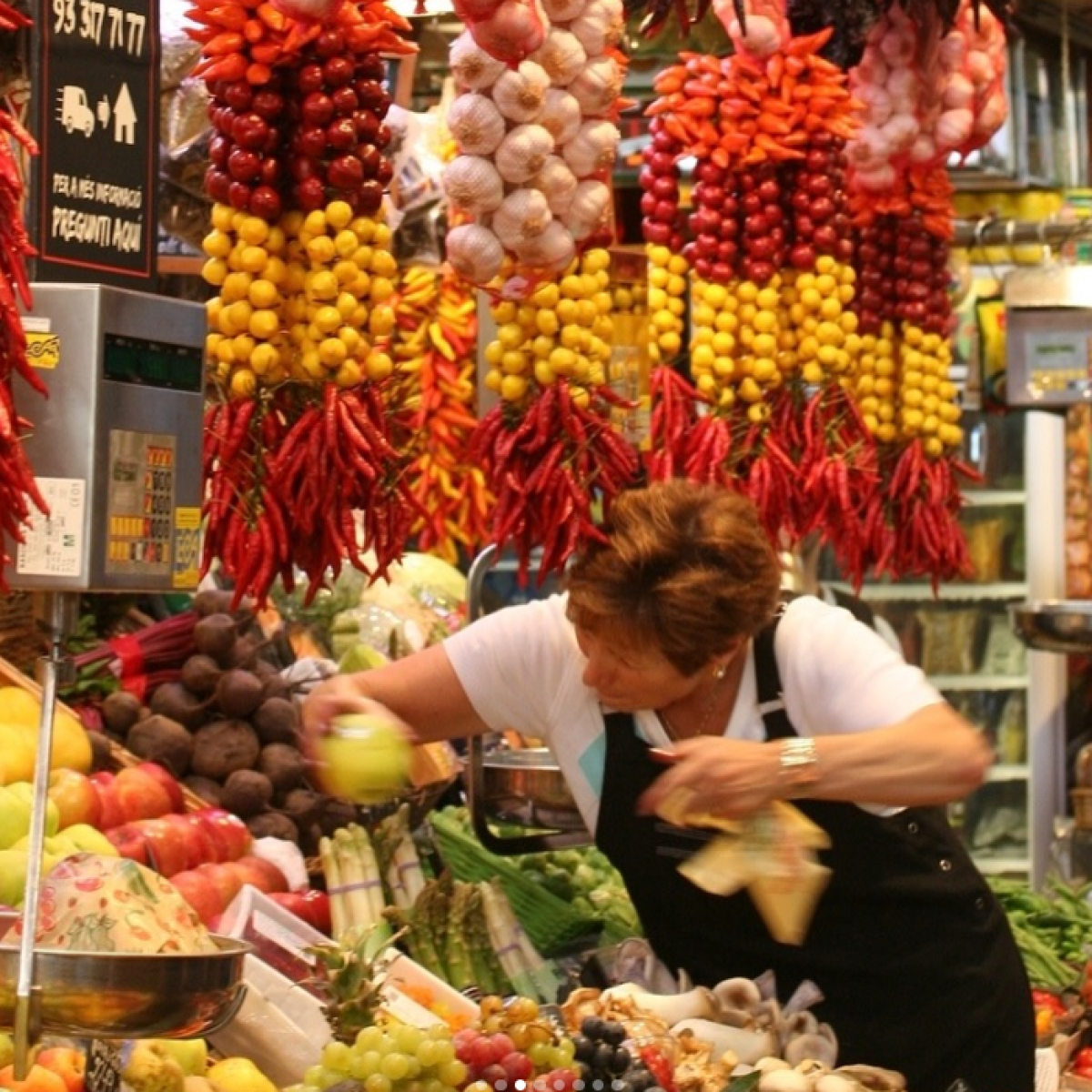 a person standing in front of a store filled with lots of fresh produce
