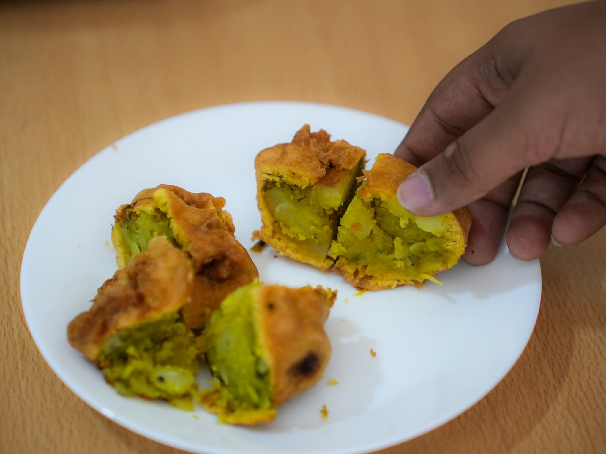 a hand holding a piece of food on a plate