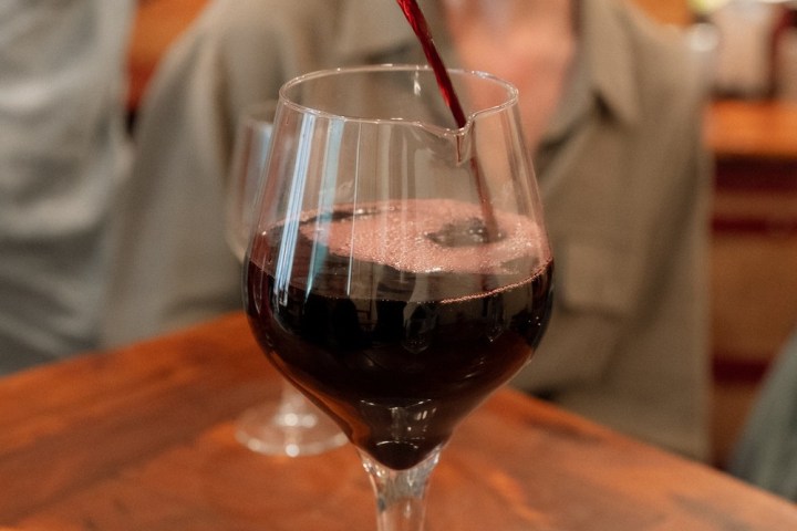 a woman sitting at a table with a glass of wine