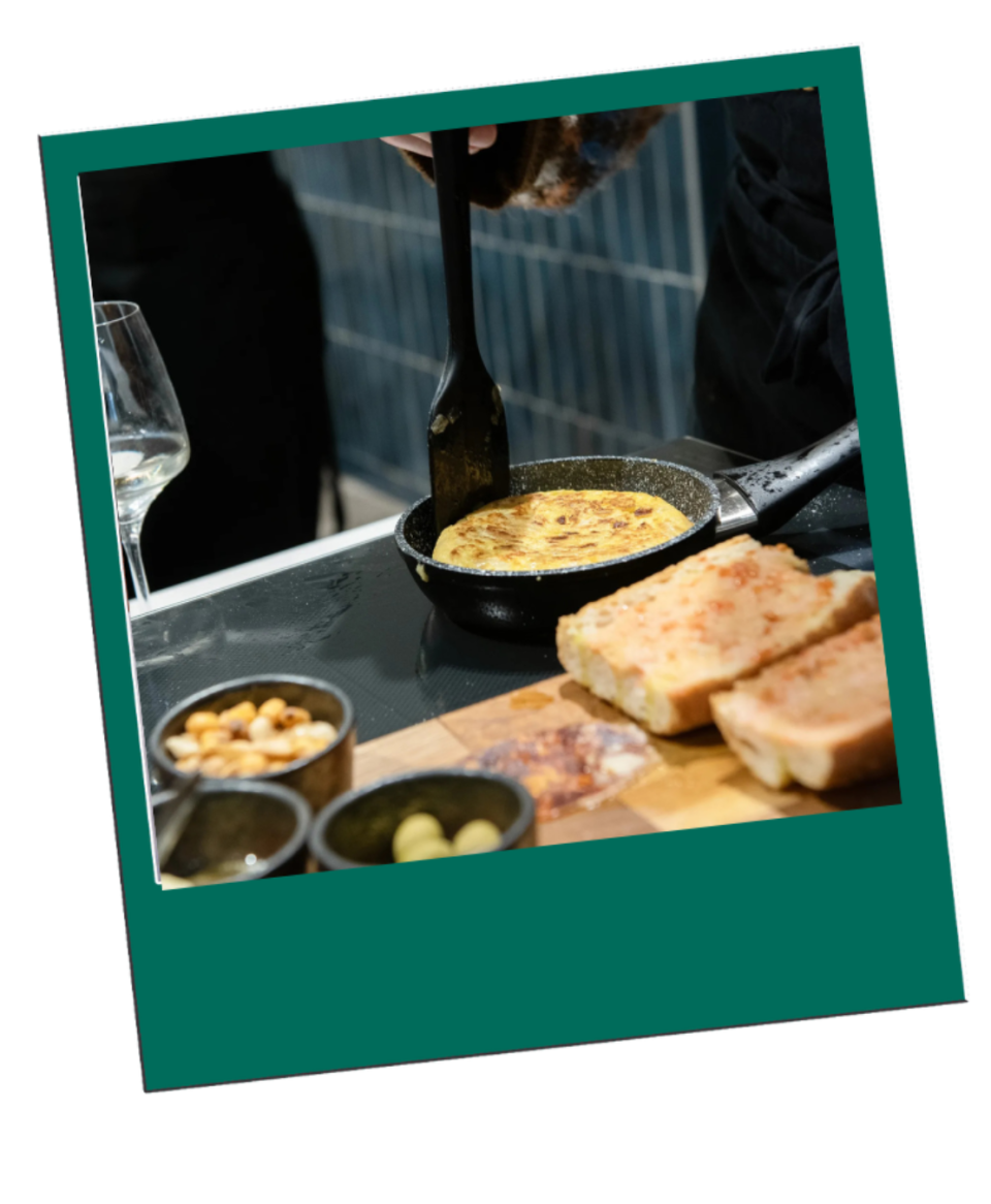 Person flipping omelet in pan near sliced bread and small bowls on table.