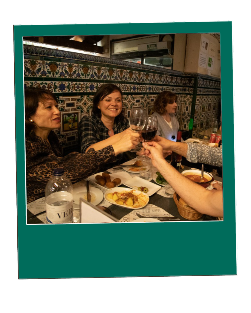 Barcelona Esmorzar de Forquilla Tour People clinking glasses at a restaurant table with food and tiled walls in the background.