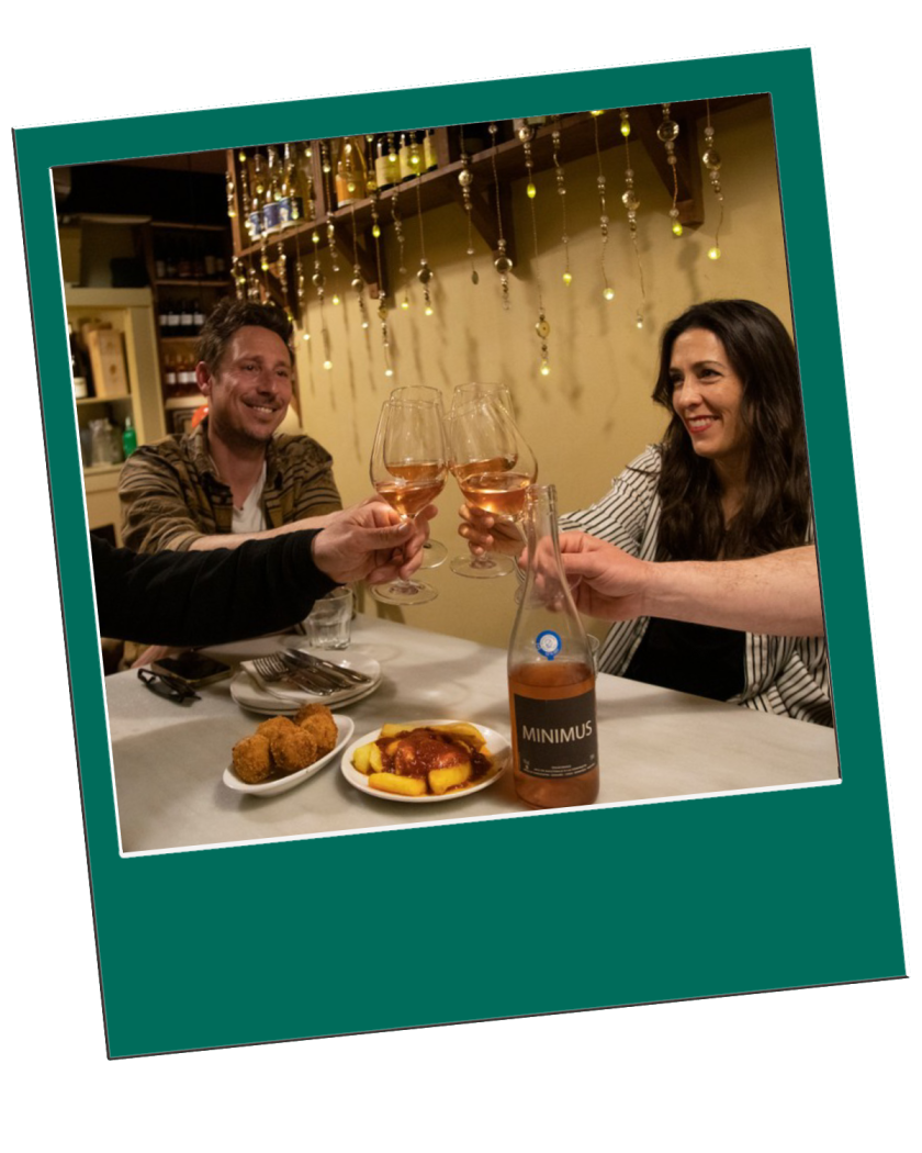 Barcelona Secret Wine Tour Three people clinking wine glasses at a table with food and a wine bottle.