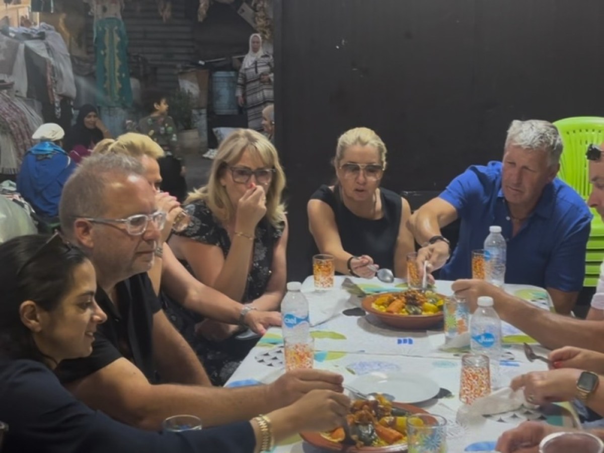 Group of people seated around a table, enjoying a meal together indoors.