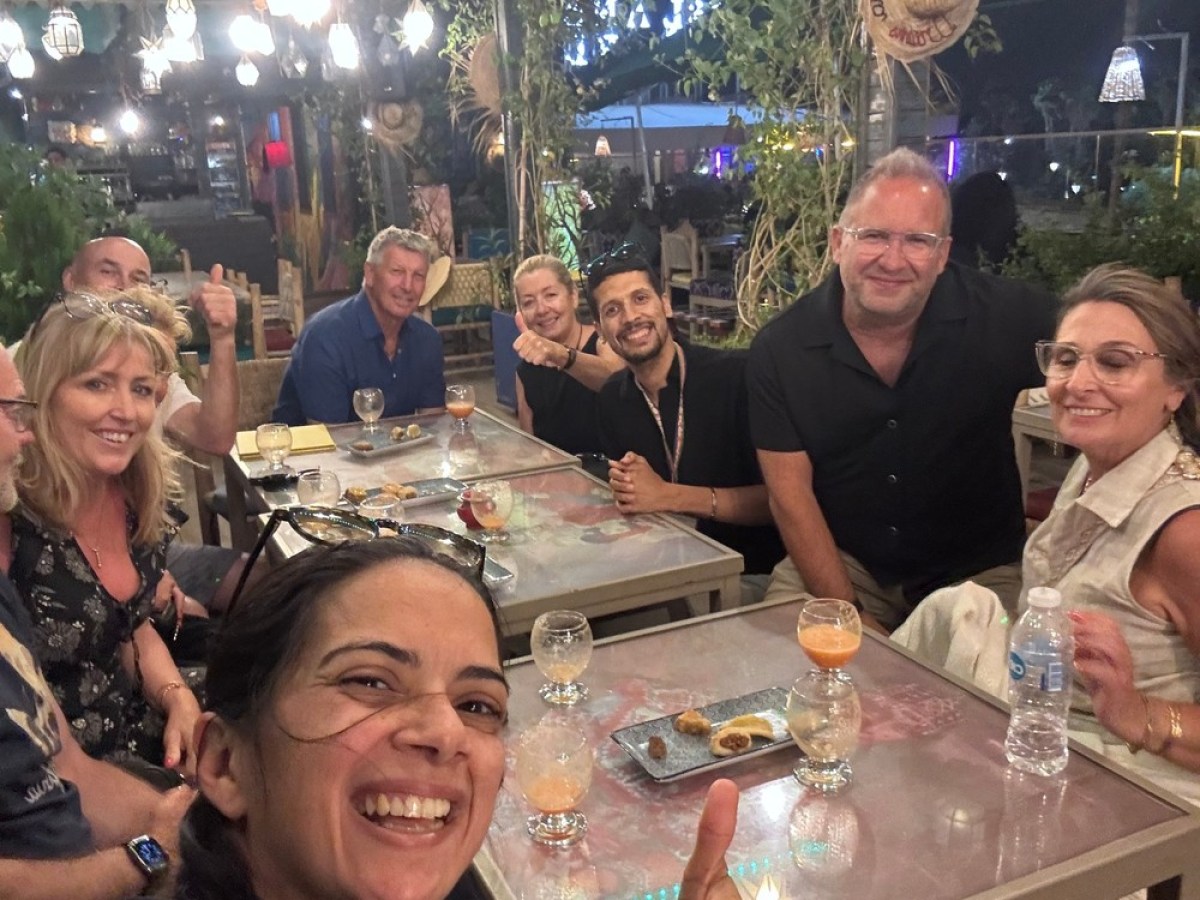 Group of people smiling and dining at a restaurant with star-shaped lights above.