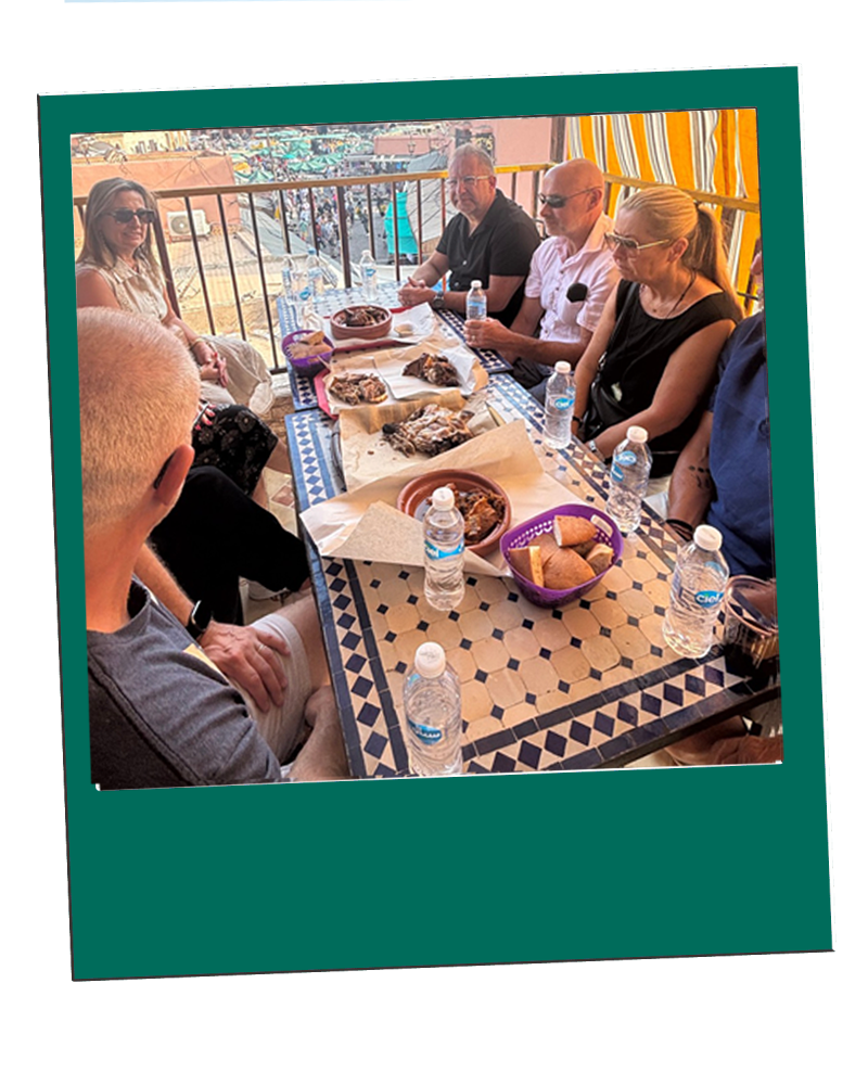 Marrakech Group of people dining at a table with food and water bottles.