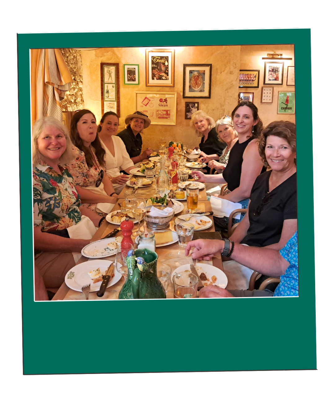 Untitled design (2) A group of people dining at a long restaurant table with art on the wall.