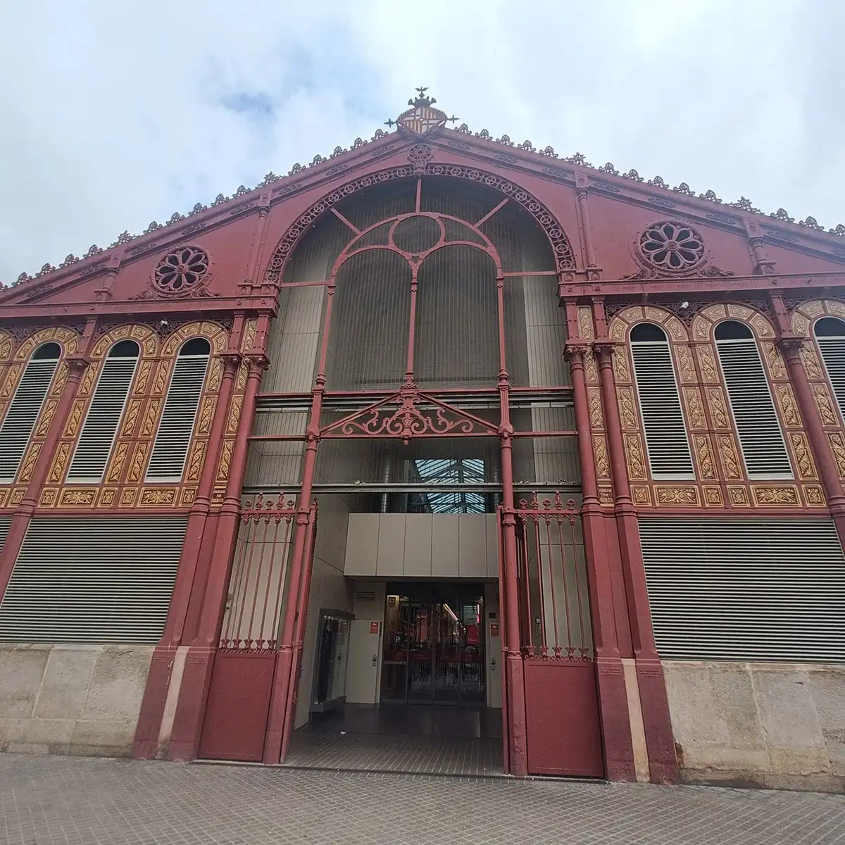Historic red and beige brick building with ornate ironwork and arched doorway.