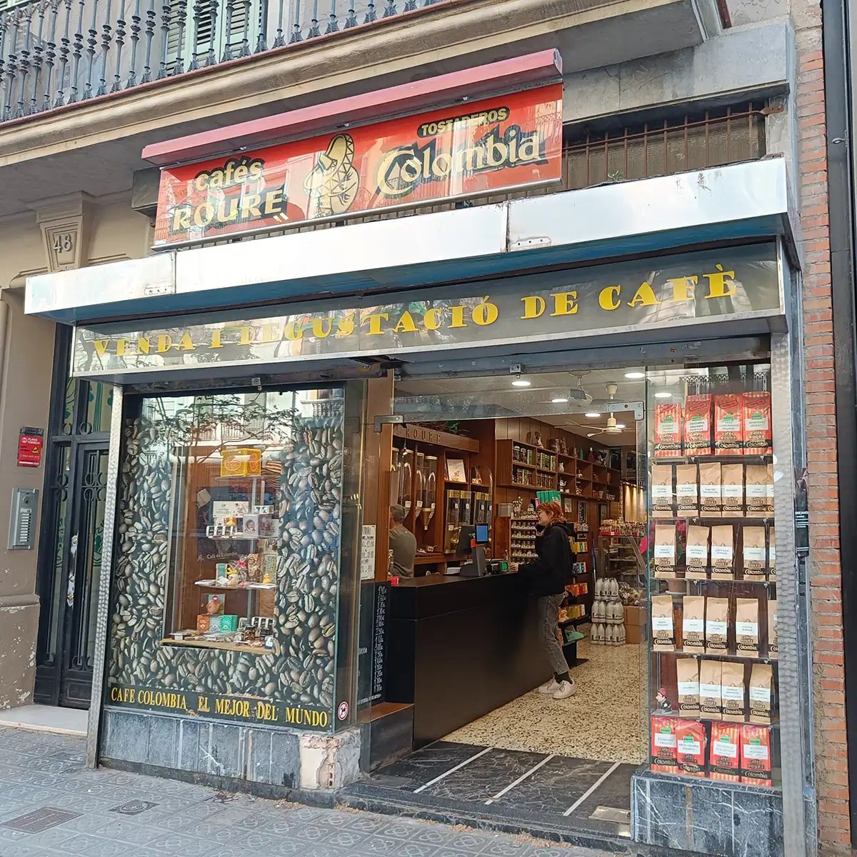 Coffee shop entrance with coffee bags displayed and a customer at the counter.