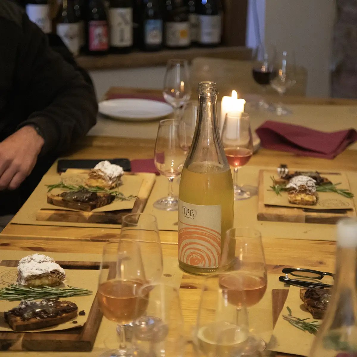 A dinner table with wine glasses, plates of food, and a bottle of wine.