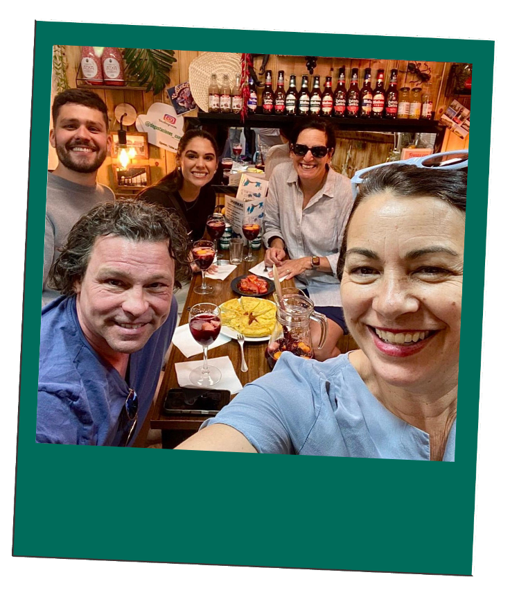 Five people smiling around a dining table with food and drinks.