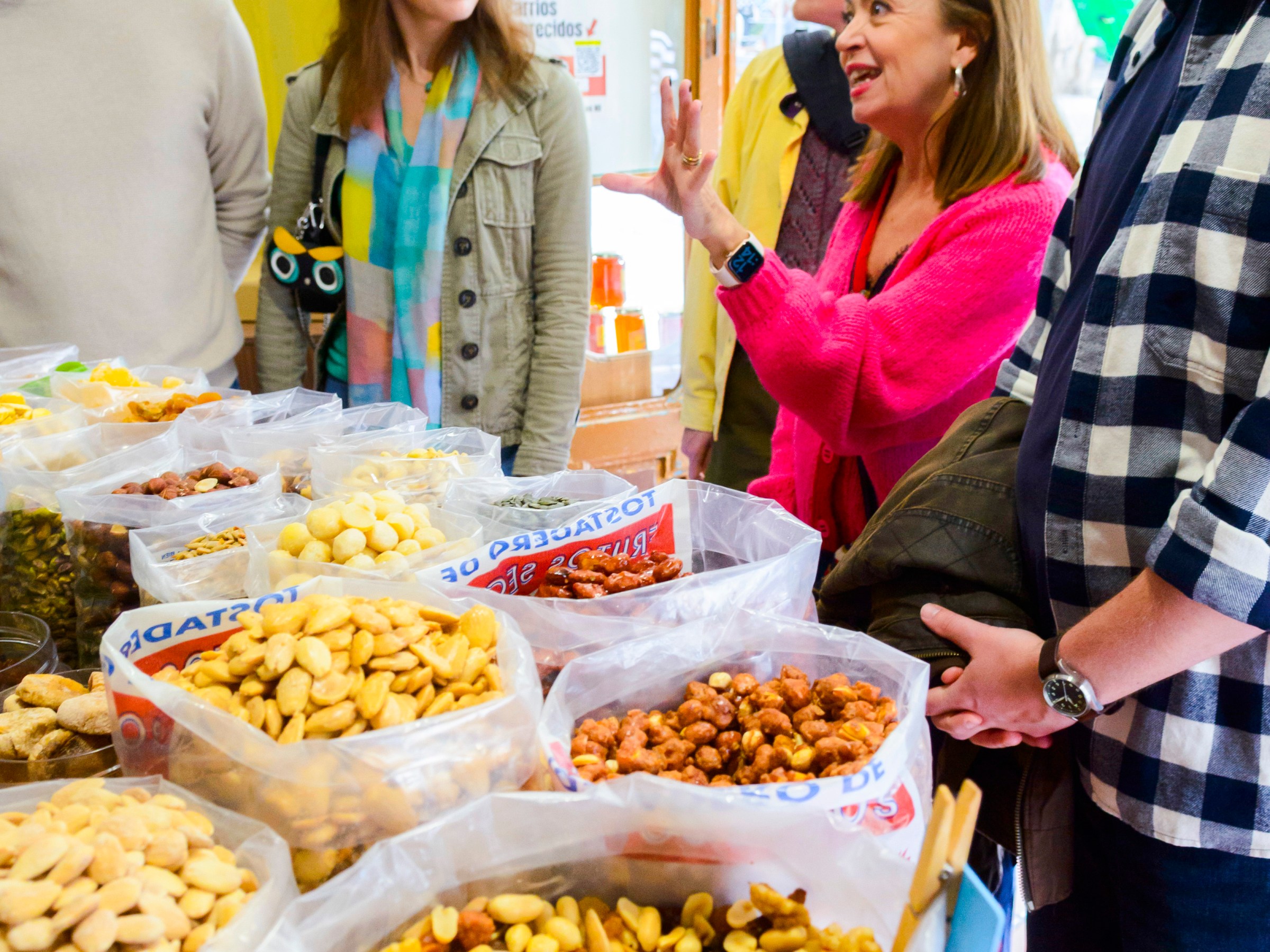 Group of people talking near bags of assorted nuts and snacks in a store.