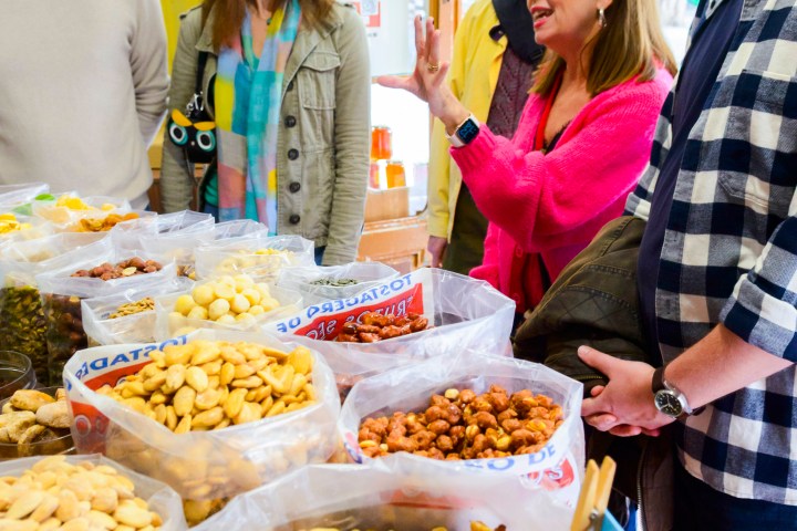 Group of people talking near bags of assorted nuts and snacks in a store.