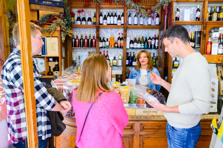 People shopping at a cozy wine and candy store, with bottles and sweets on display.