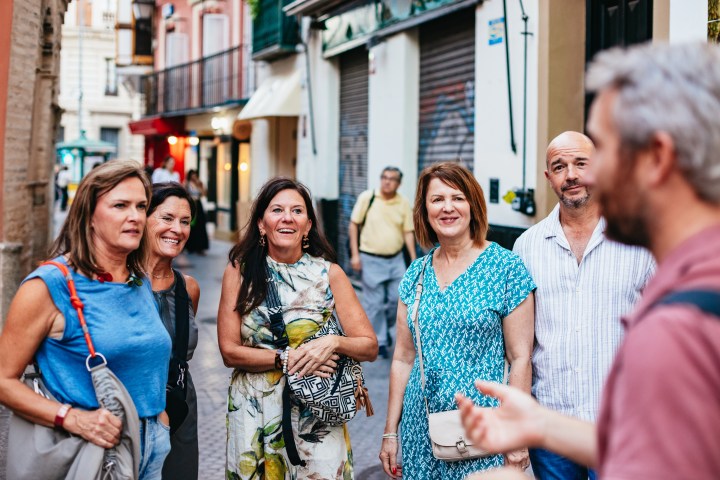 Group of people smiling and talking in a lively street.