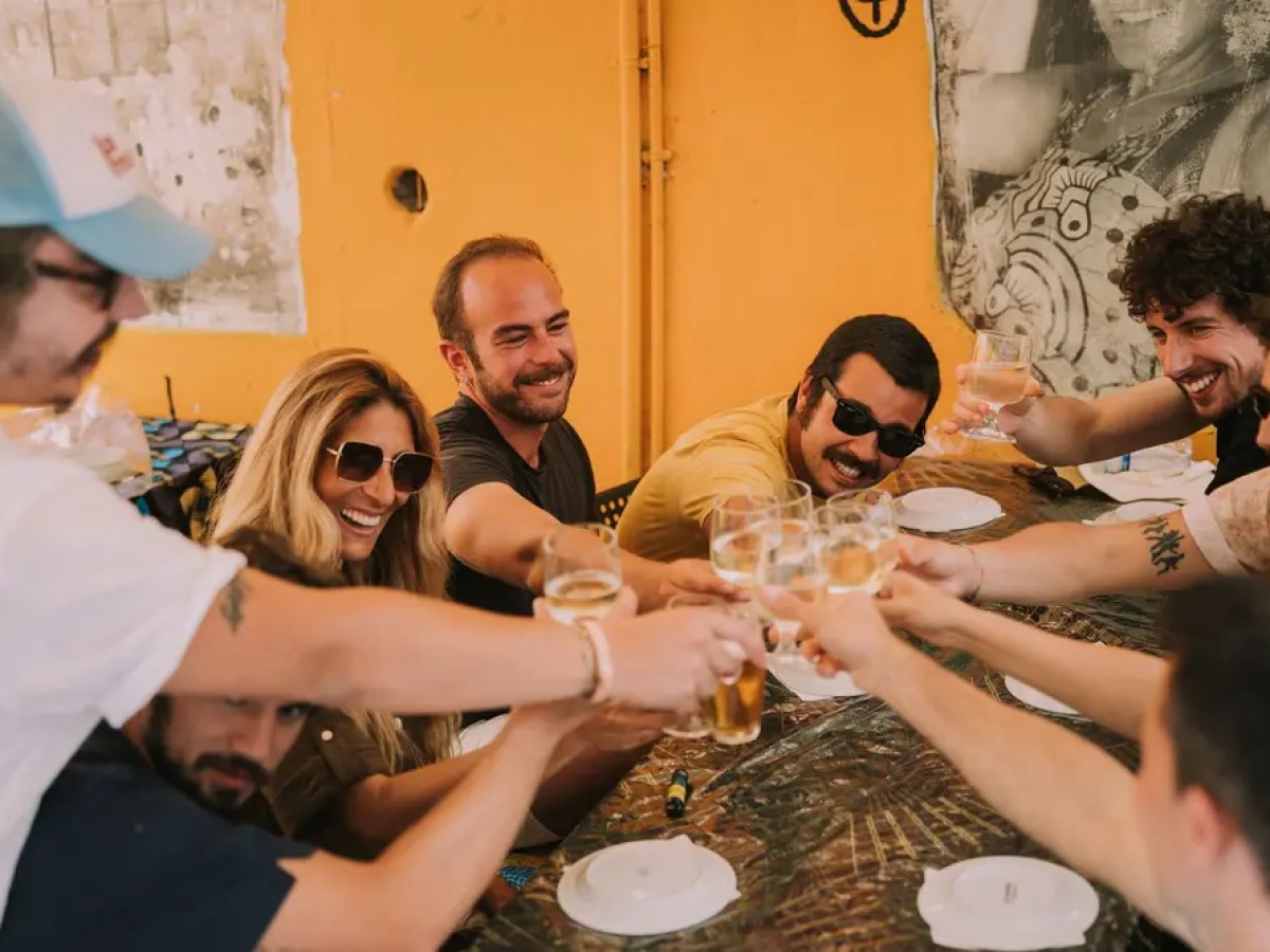 Group of people toasting with drinks at a table.