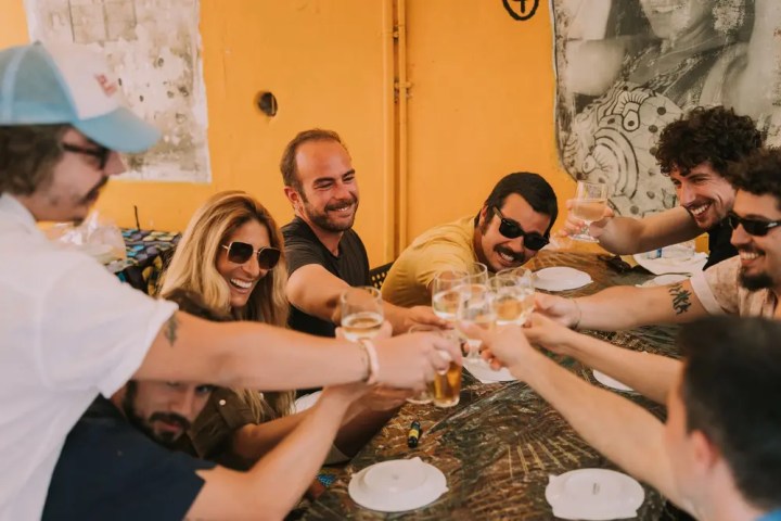 Group of people toasting with drinks at a table.