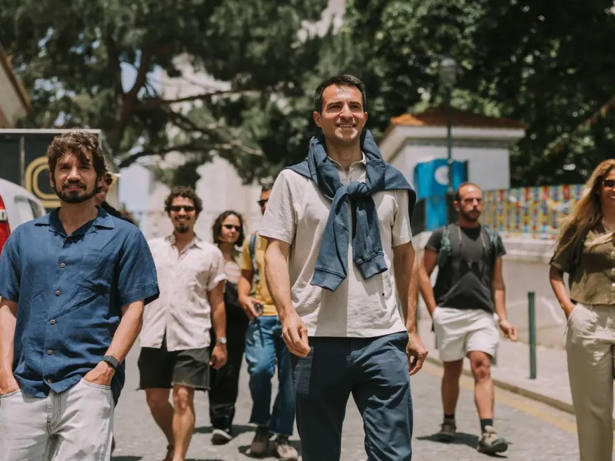 Group of people walking outdoors on a sunny day with trees around.