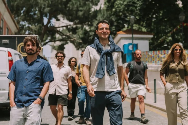 Group of people walking outdoors on a sunny day with trees around.