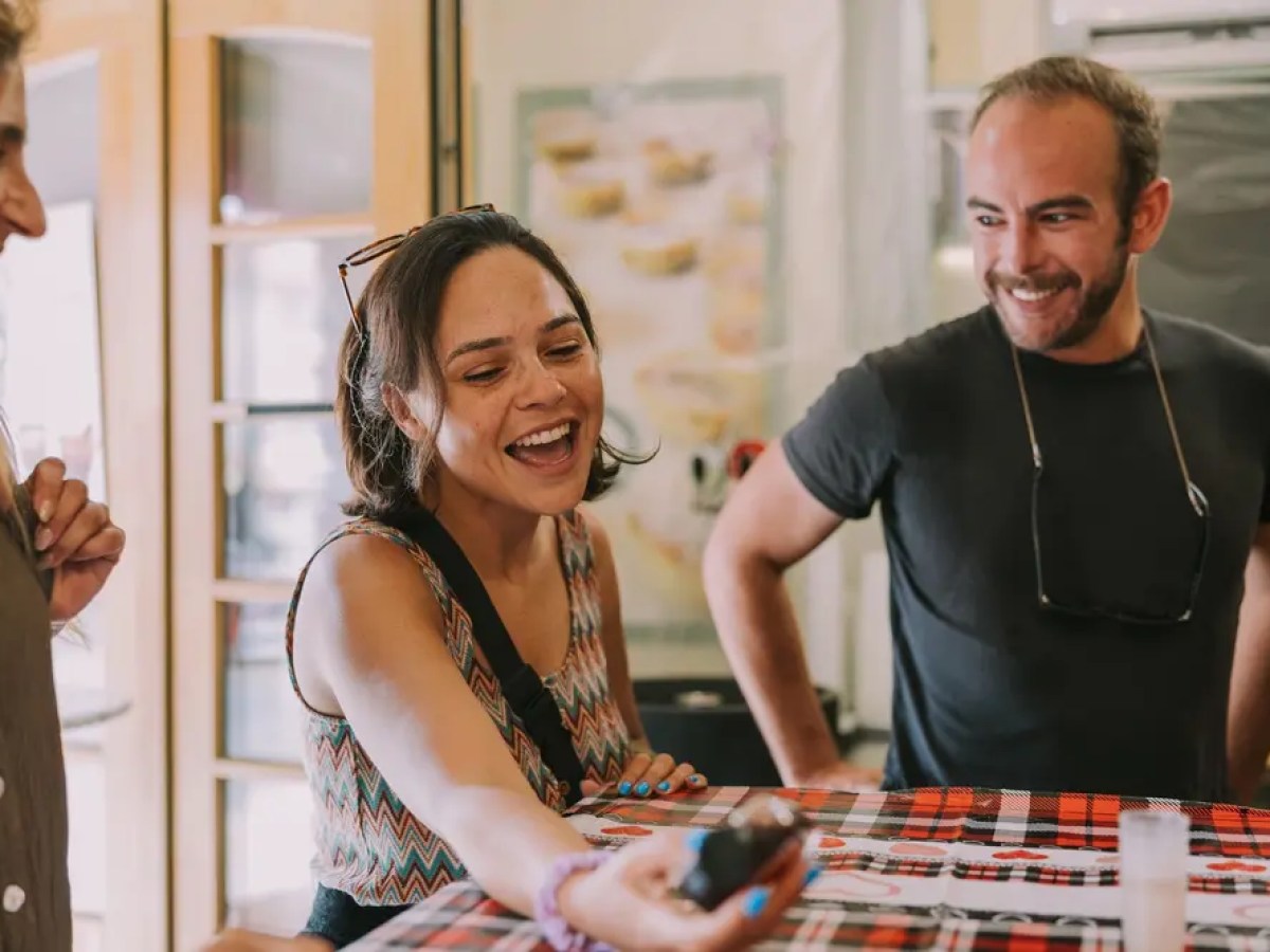 Three people smiling and laughing together at a table.