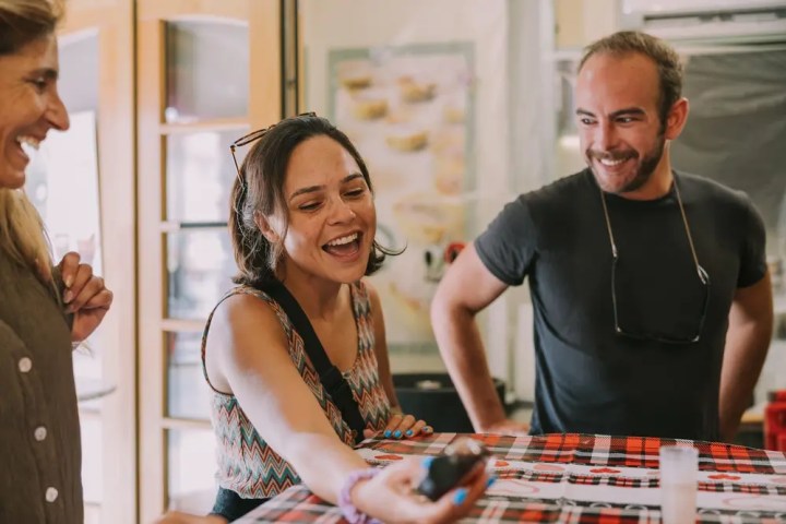 Three people smiling and laughing together at a table.